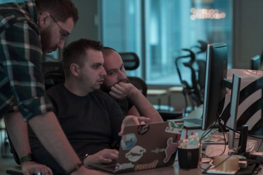 A photo of three men staring intently at a computer while sitting in a modern office. Selective focus. High-quality photo