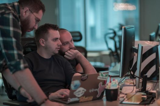 A photo of three men staring intently at a computer while sitting in a modern office. Selective focus. High-quality photo