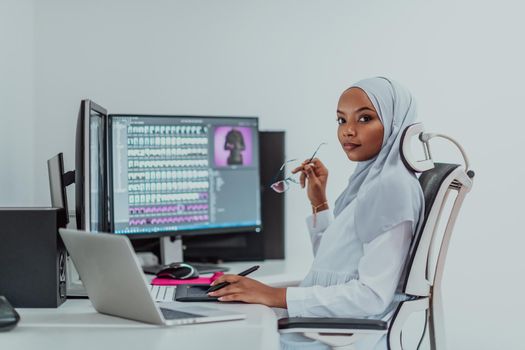 Young Afro-American modern Muslim businesswoman wearing a scarf in a creative bright office workplace with a big screen. High-quality photo