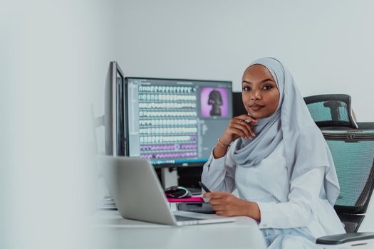 Young Afro-American modern Muslim businesswoman wearing a scarf in a creative bright office workplace with a big screen. High-quality photo