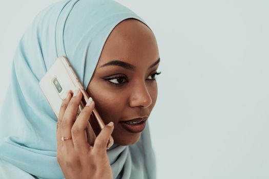 An African Muslim woman using a smartphone on a white background. High-quality photo