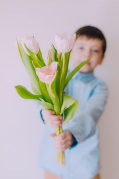 A boy with a bouquet of tulips lifestyle . Postcard for March 8. Congratulations on Women's Day. Congratulations on Mother's Day. Flowers are tulips. Baby and flowers