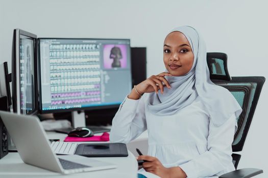 Young Afro-American modern Muslim businesswoman wearing a scarf in a creative bright office workplace with a big screen. High-quality photo