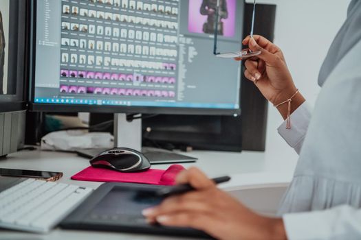 Young Afro-American modern Muslim businesswoman wearing a scarf in a creative bright office workplace with a big screen. High-quality photo