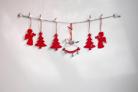 Christmas composition. A garland of red wooden toy fir trees and a rolling horse on a rough rope on a white background. Christmas, winter, new year concept. Flat, top view, copy space