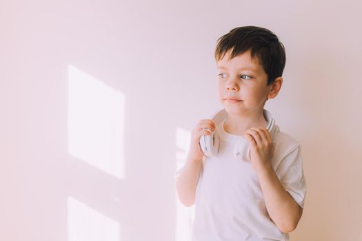 The boy listens to music with lifestyle headphones . Modern technologies. Kids and gadgets. Music for children. Modern children. Smartphones in children. Copy space. White background.