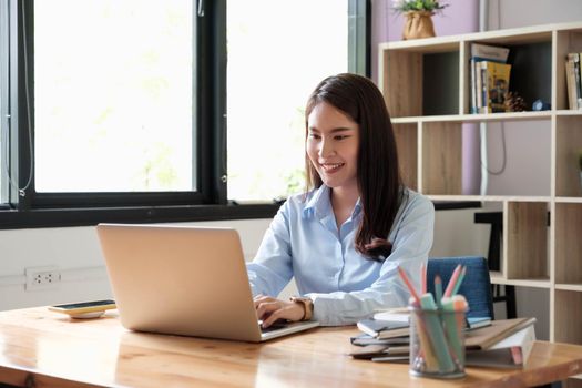 Portrait of young woman using laptop, she is working on laptop computer at a coffee shop.