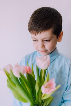 A boy with a bouquet of tulips lifestyle . Postcard for March 8. Congratulations on Women's Day. Congratulations on Mother's Day. Flowers are tulips. Baby and flowers