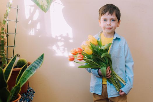 A boy with a bouquet of tulips lifestyle . Postcard for March 8. Congratulations on Women's Day. Congratulations on Mother's Day. Flowers are tulips. Baby and flowers