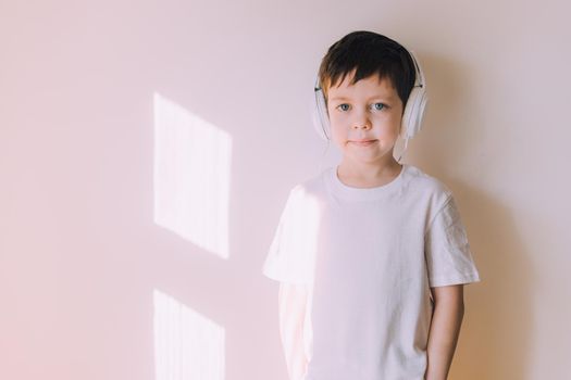 The boy listens to music with lifestyle headphones . Modern technologies. Kids and gadgets. Music for children. Modern children. Smartphones in children. Copy space. White background.