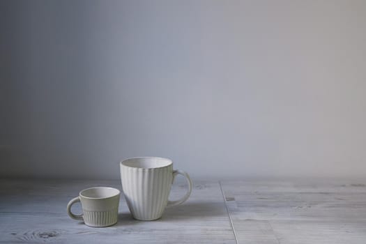 Minimalistic Scandinavian style. Two cups of coffee or tea of different sizes for two on on the table. Empty space.