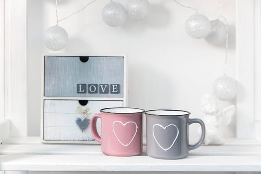 Small chest of drawers with two drawers with the words "love". Pink and gray cup with heart for Valentine's Day