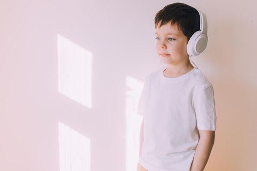 The boy listens to music with lifestyle headphones . Modern technologies. Kids and gadgets. Music for children. Modern children. Smartphones in children. Copy space. White background.