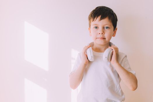 The boy listens to music with lifestyle headphones . Modern technologies. Kids and gadgets. Music for children. Modern children. Smartphones in children. Copy space. White background.