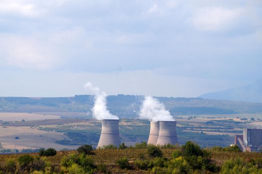 smoking chimneys of a thermal power plant against the backdrop of a mountainous landscape in Bulgaria.