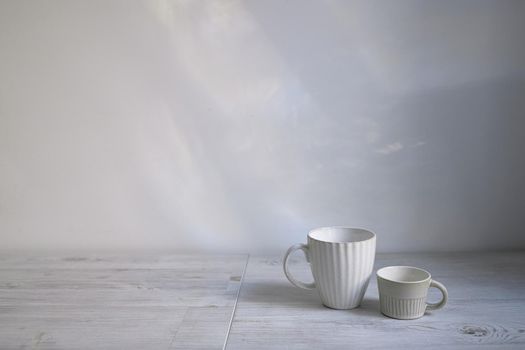 Minimalistic Scandinavian style. Two cups of coffee or tea of different sizes for two on on the table. Empty space.