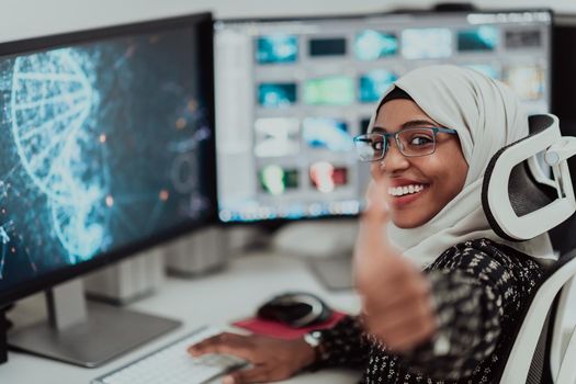 Young Afro-American modern Muslim businesswoman wearing a scarf in a creative bright office workplace with a big screen. High-quality photo