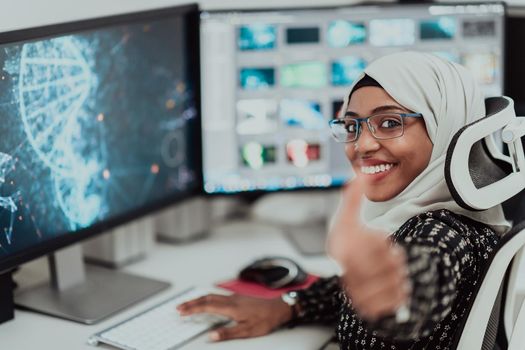 Young Afro-American modern Muslim businesswoman wearing a scarf in a creative bright office workplace with a big screen. High-quality photo