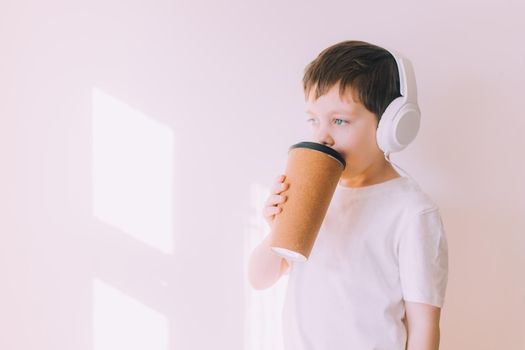 The boy listens to music with lifestyle headphones . Modern technologies. Kids and gadgets. Music for children. Modern children. Smartphones in children. Copy space. White background.