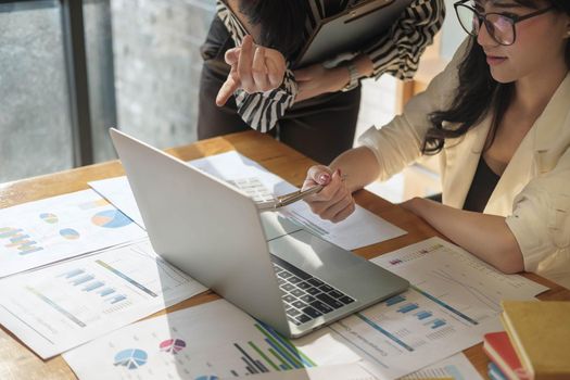 Business people meeting in office and discussing over a documents, two woman with a financial report with partner colleague on laptop computer.