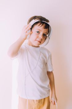 The boy listens to music with lifestyle headphones . Modern technologies. Kids and gadgets. Music for children. Modern children. Smartphones in children. Copy space. White background.