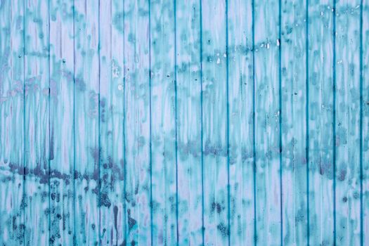 Log fence painted in blue paint, faded from time to time