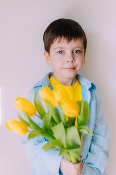 A boy with a bouquet of tulips lifestyle . Postcard for March 8. Congratulations on Women's Day. Congratulations on Mother's Day. Flowers are tulips. Baby and flowers