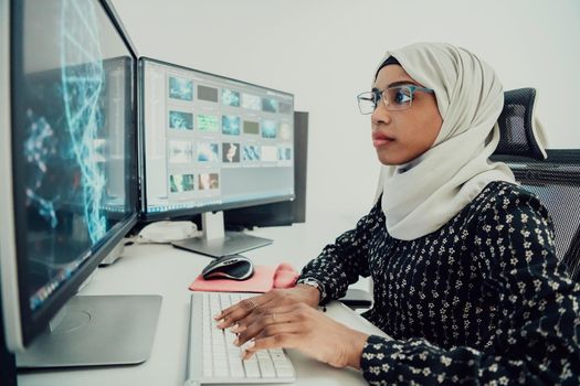 Young Afro-American modern Muslim businesswoman wearing a scarf in a creative bright office workplace with a big screen. High-quality photo