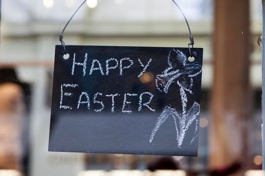 The inscription Happy Easter is written in chalk on a slate board.