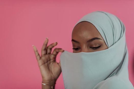 Portrait of young modern muslim afro beauty wearing traditional islamic clothes on plastic pink background. Selective focus. High quality photo