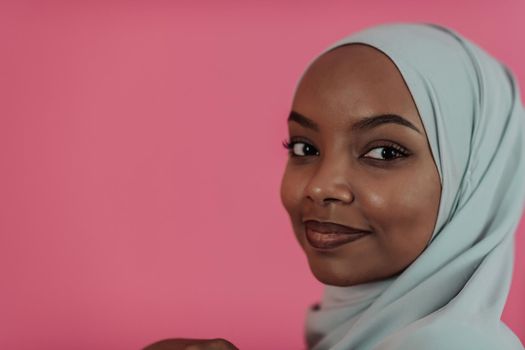 Portrait of young modern muslim afro beauty wearing traditional islamic clothes on plastic pink background. Selective focus. High quality photo