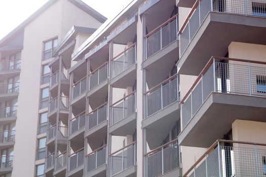 facade of modern residential apartment building with glass balconies in sunlight.