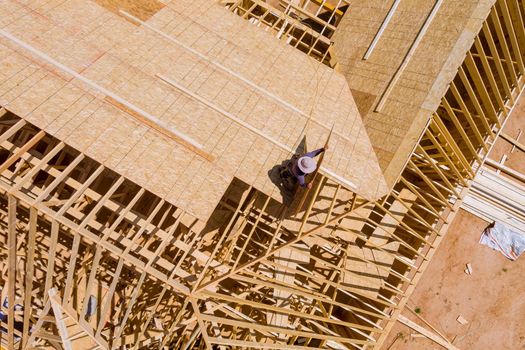 Top view of construction worker putting the plywood with nail gun on a house building development