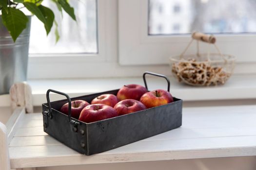 Six red apples on a zinc gray tray to eat on a white wooden table.