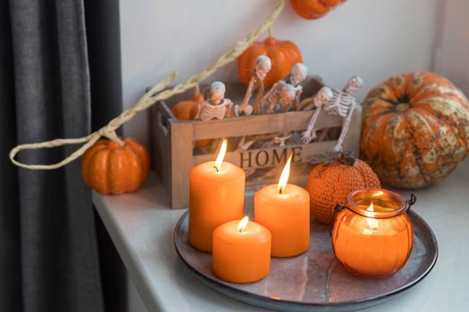 Porcelain and natural pumpkins, orange candles on a white table, Halloween decorations.