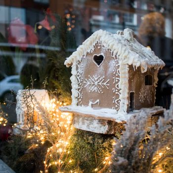 Homemade gingerbread house and Christmas spices with ornament. Reflections in a shop window