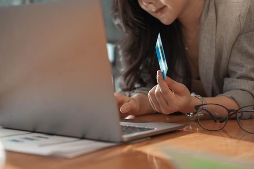Asian woman makes a purchase on the Internet on the laptop computer with credit card.