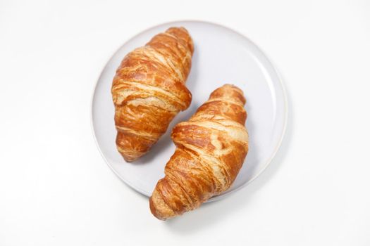 Freshly baked croissant on gray round plate on white background