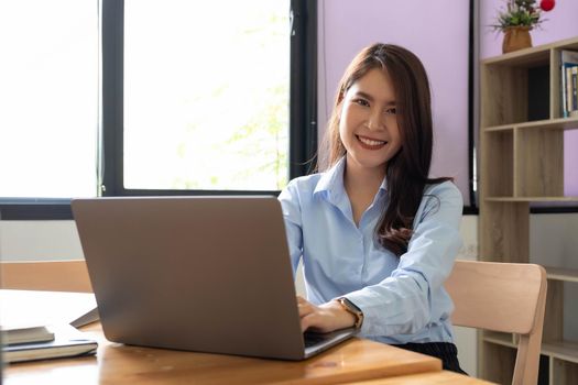 Portrait of young woman using laptop, she is working on laptop computer at a coffee shop.