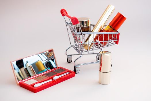 Front view of a shopping cart with makeup products on a pink background. Cosmetic shopping concept. photo