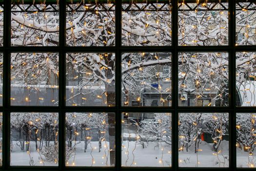 Window overlooking the snowy city. Christmas tree in the foreground