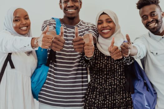 Group portrait of happy African students standing together against a white background and showing ok sign thumbs up girls wearing traditional Sudan Muslim hijab fashion. High-quality photo