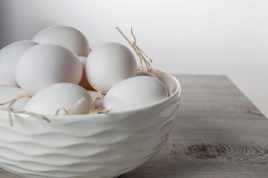 Patterned bowl with eggs on beige wooden table in white scandinavian style kitchen. Place for text. Copy space