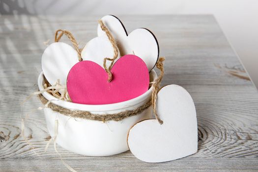 White and red wooden hearts in a ceramic bowl filled with paper. Place for your text