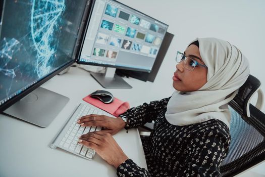 Young Afro-American modern Muslim businesswoman wearing a scarf in a creative bright office workplace with a big screen. High-quality photo