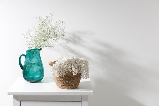 Large glass green jug with a bouquet of gypsophila wicker basket with white knitted lace. Place for text. Copy space