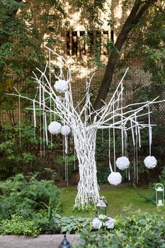 White painted tree with hanging balls, installation in the park.