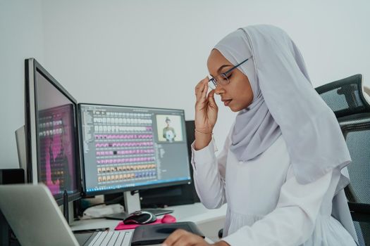 Young Afro-American modern Muslim businesswoman wearing a scarf in a creative bright office workplace with a big screen. High-quality photo