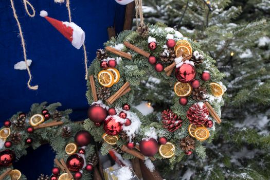 Christmas wreath of fir branches with decorations hanging on the wall of the house