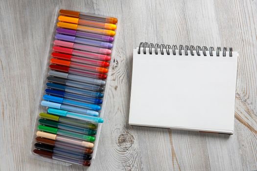 View from above. Twenty-four colored markers and a notebook are on the drawing table.